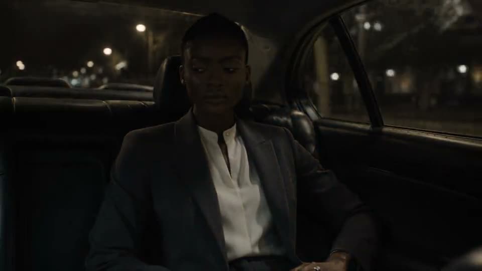 A person in a suit, seated in the back of a car.